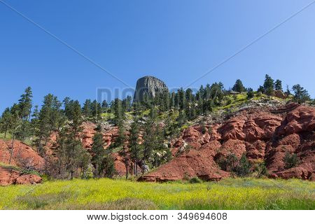 Looking Past The Sedimentary Layers Of Earth That Is Covered With Trees And Wild Grass To The Peak O