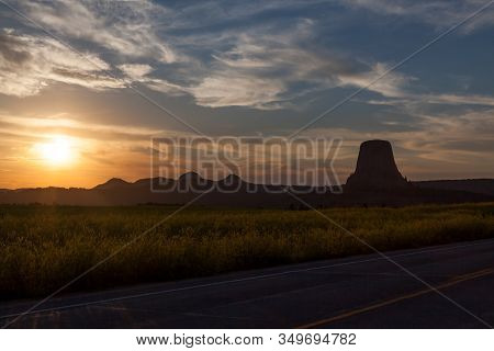 Late Afternoon Sunshine Through Light Clouds Casting A Soft Glow On The Landscape And Road To Devils