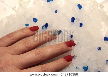 Female Hand In White Crystals. Female Hand With A Red Manicure. White Stone