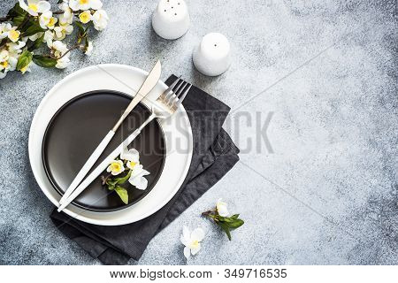 Spring Table Setting With White Plate, Cutlery And Bloossom Flower. Top View On Kitchen Table.