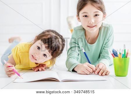 Happy Two Little Girl Drawing And Do Homework On The Flloor