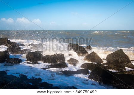 Pier At Corner Of Holland, With Basalt Blocks And Splashing And Foamy North Sea Water In The Winter 