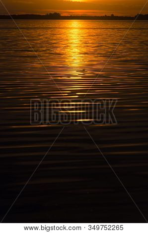 Sunset In Chascomus, The Orange Sun Is Reflected On The Surface Of The Lake. Province Of Buenos Aire