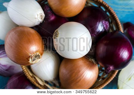 Red, White And Yellow Onions In A Wicker Basket Close-up View From Above