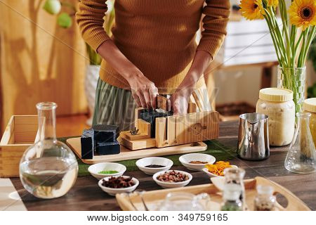 Woman Cutting Big Black Handmade Soap Bar Into Small Pieces