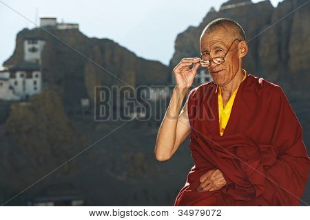 Indické staré tibetského mnicha v červené barvě oblečení s brýle před klášter