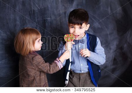 Little Syster Gives A Brother Candy Red Lollipop. Boy And Girl With Sweet Food
