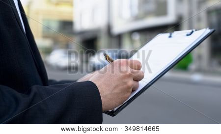 Male Realtor Writing Up List Of Potential Buyers, Mortgage Decision Queue