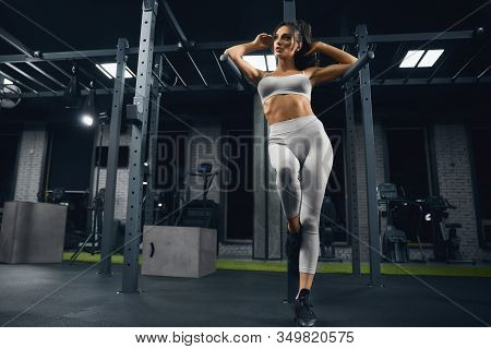 From Above View Of Female Bodybuilder In Beige Sportswear Posing Near Parallel Bars. Srtong Woman Wi