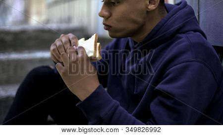 Hungry Afro-american Teenager Eagerly Eating Sandwich, Poor Family, Crisis