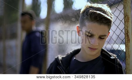 Upset Teen Boys Leaning On Metal Fence, Abandoned With Society, Orphanage