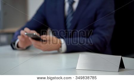 Businessman Scrolling On Smartphone In Office, Blank Nameplate Template For Text