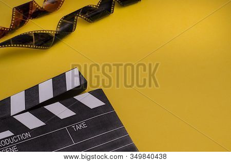 Clapper Board And Film Strip On A Bright Yellow Background With Copy Space. For Articles About The M