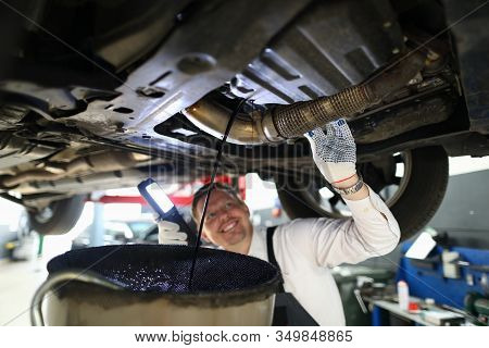 Mechanic Conducts Thorough Inspection Car Garage. Male Mechanic In Working Overall Stands Under Car 
