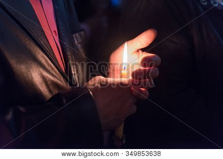 Closeup Of People Holding Candle At Night During Church Service