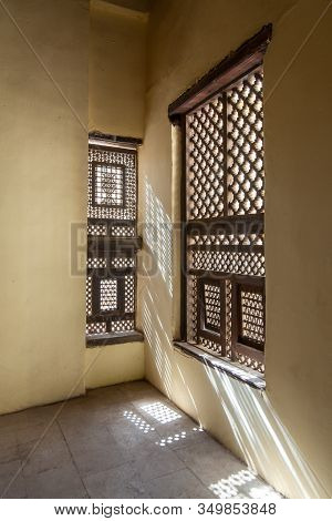 Corner Of Two Interleaved Grunge Wooden Ornate Windows - Mashrabiya - In Stone Wall At Abandoned Bui
