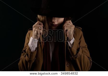 Retro Gangster Woman In A Brown Cloak And Black Hat. Photoshoot In The Style Of The Mafia. Dark Blur