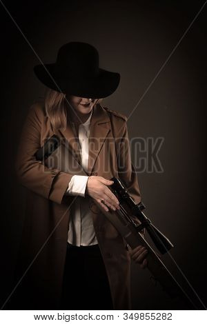 A Woman In A Brown Cloak And A Black Hat With Airguns In Her Hands Looks Into The Sight. Gangster St