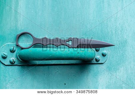 Black Knife On A Turquoise Background. Bright Turquoise Background And Knife.