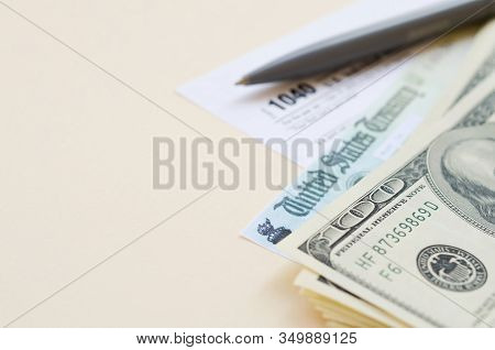 1040 Individual Income Tax Return Form With Refund Check And Hundred Dollar Bills On Beige Backgroun