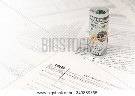1065 U.s. Return Of Parentship Income Form With Roll Of American Dollar Banknotes