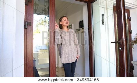 Beautiful Woman Standing By House And Smiling, Waiting For Husband From Work