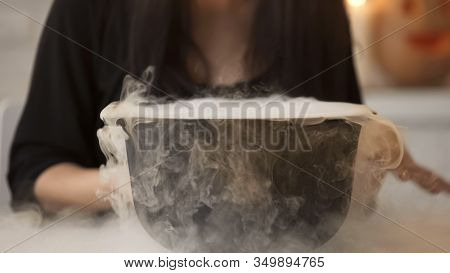 Witch Conjuring, Putting Magic Spell And Cooking Potion In Pot With White Smoke