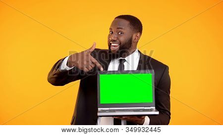 Cheerful Black Manager Showing At Prekeyed Laptop, Place For Advertisement