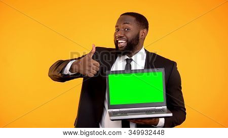 Happy Smiling Afro-american Male Showing Prekeyed Laptop And Thumbs-up Gesture