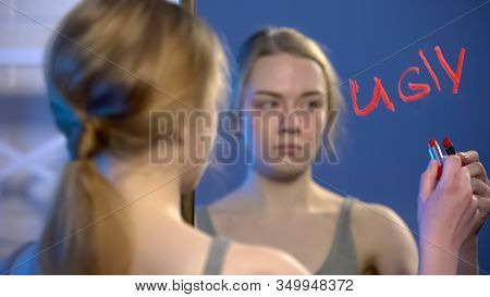 Upset College Student Writing Word Ugly By Lipstick On Mirror, Bullying Problem