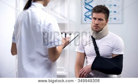 Traumatologist Making Prescriptions To Accident Victim, Bandages On Neck And Arm