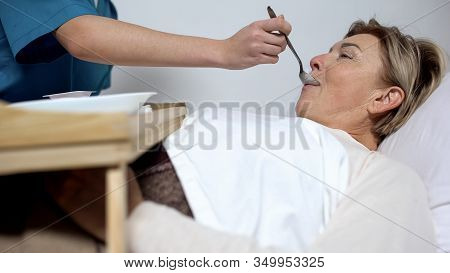 Nurse Feeding Disabled Mature Woman With Porridge, Care For Patients, Hospice