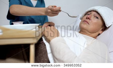 Terminally Ill Woman Looking At Camera, Nurse Feeding Patient, Alzheimer Disease