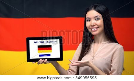 Lady Holding Tablet With Learn German App, Germany Flag On Background, Education