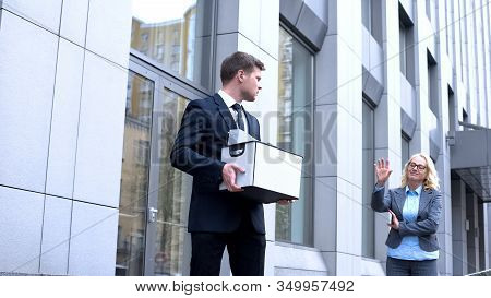 Sad Male Manager With Stuff Box Looking Gloating Female Boss, Company Dismissal