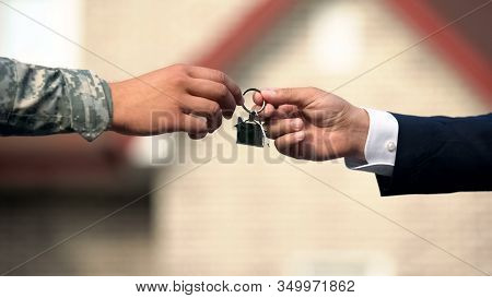 Man In Business Suit Giving House Key To Man In Military Uniform, State Support