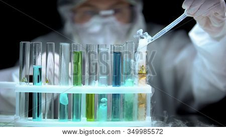 Scientist Dropping Sample To Liquid Boiling In Test Tube With Warning Symbol