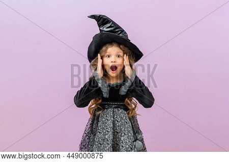 A Surprised And Joyful Sorceress In A Black Fancy Dress On An Isolated Background. A Little Girl In