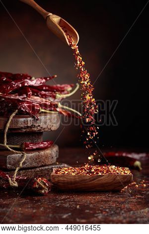 Chilli Flakes Are Poured Into A Wooden Dish. Chilli Flakes And Dried Chili Peppers On A Brown Backgr