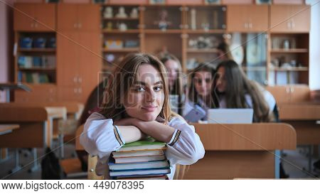 A Student Poses With Textbooks At Her Desk In Her Class.
