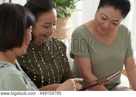 Senior Woman Explaining Her Friends How To Use New Appllication For Online Shopping And Communicatio