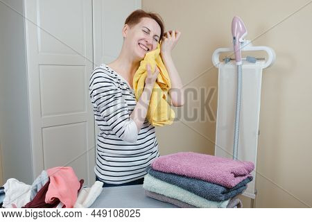 Housewife Woman Put A Clean Towel To Her Face. Softness Of Freshly Washed Clothes.