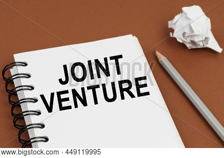 Business And Finance Concept. On A Brown Surface Lies A Pen, Crumpled Paper And A Notepad With The I