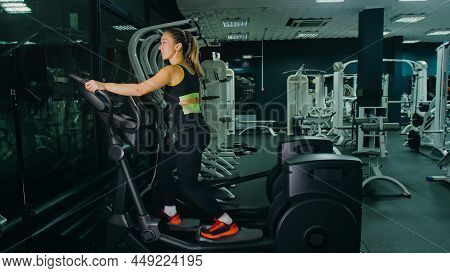 Fit Athletic Woman Exercising On An Elliptical Machine. Muscular Women Activity Training In Modern G