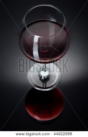 A glass filled with wine on a black table