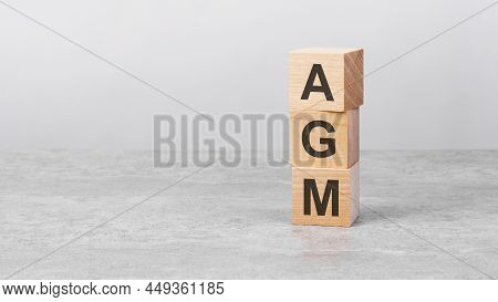 Wooden Cube On A White Table With Text Agm. Concept Of Business, Financial, Investment, Economy. Cop