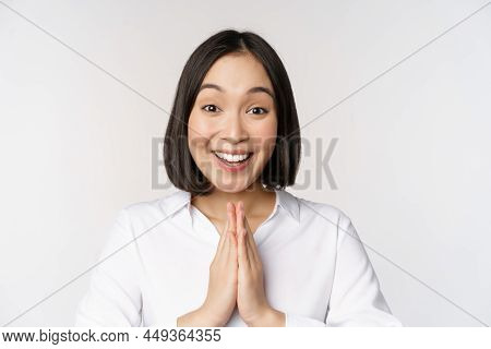 Close Up Portrait Of Young Japanese Woman Showing Namaste, Thank You Arigatou Gesture, Standing Over