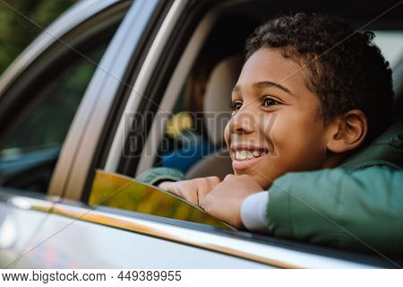 Black boy wearing jacket smiling and looking foreword while sitting in car