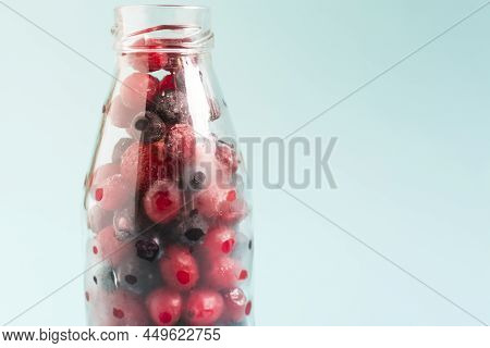 A Mixture Of Frozen Black And Red Berries In A Transparent Bottle Close-up On A Light Background. Th