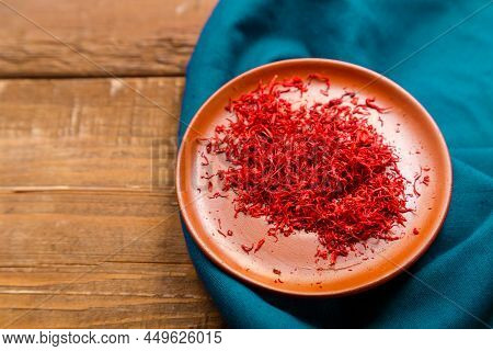 Saffron In A Clay Plate On A Blue Napkin On A Wooden Table. Horizontal Photo